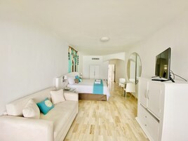 Un dormitorio moderno con cama, sofá, televisor y espejo.