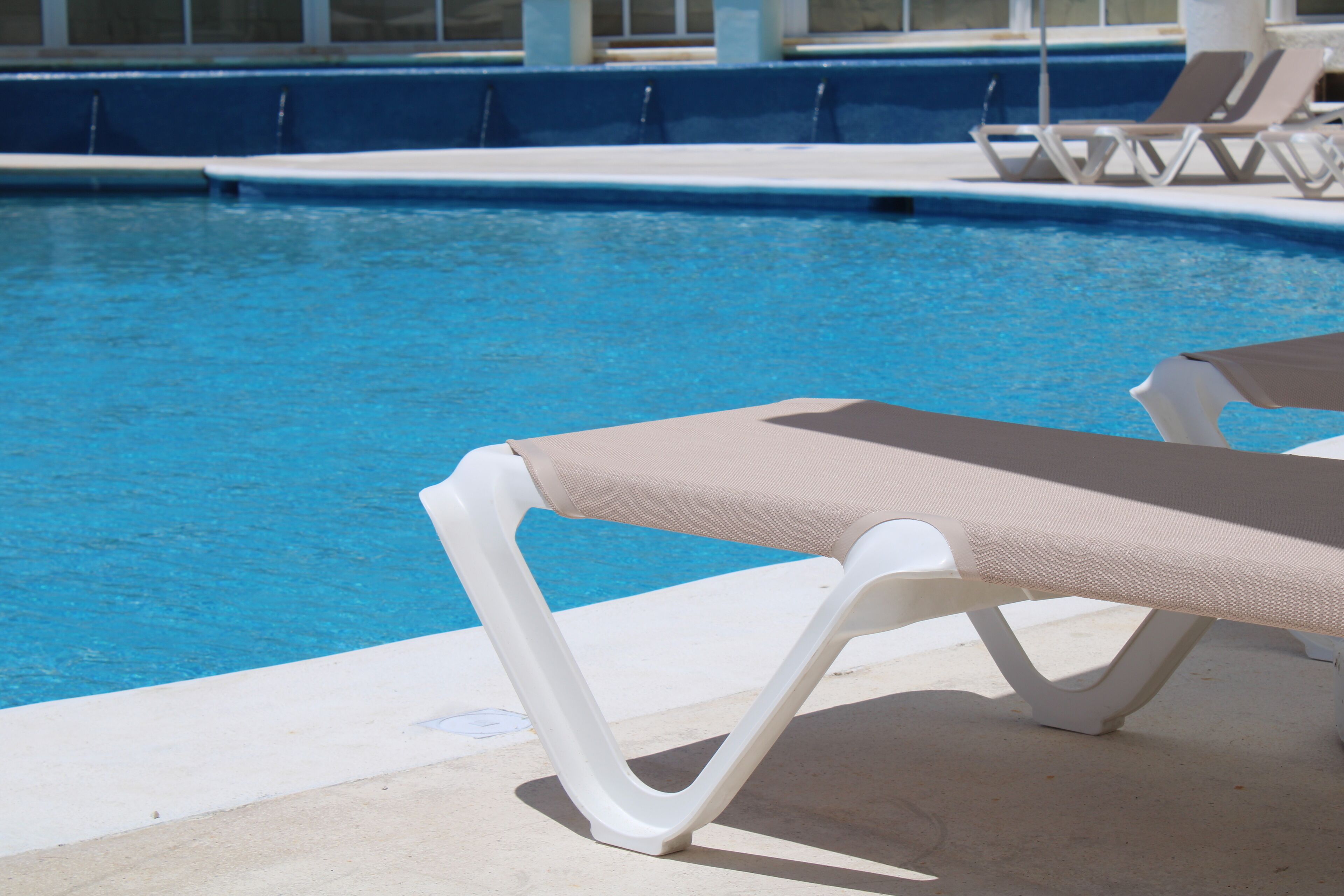 A swimming pool with lounge chairs and a clear blue water surface.