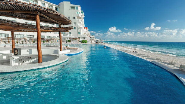 A resort pool with a beach view, a covered seating area, and a building with multiple balconies. - Cyan Cancun Resort & Spa  (Cancun)