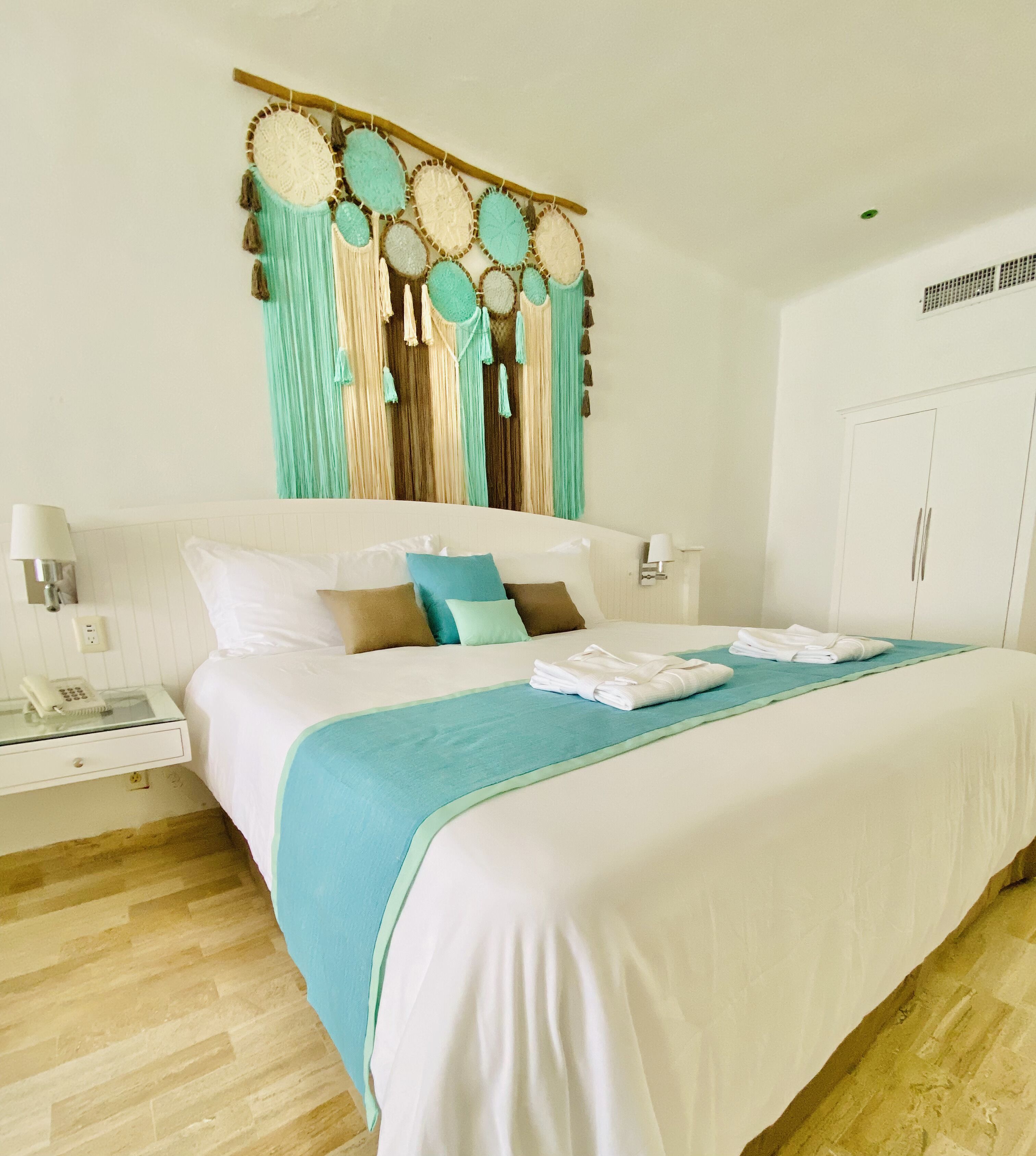 A hotel room with a large bed, a nightstand with a phone, and a wall decoration above the bed.