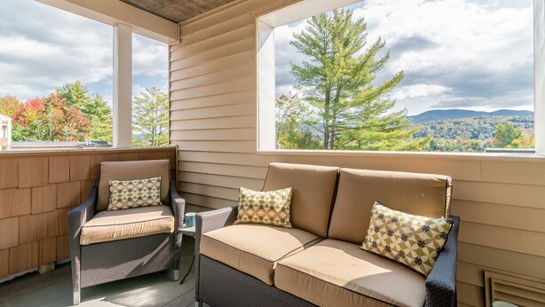 A covered porch with a sofa and armchair, large windows, and a view of trees and hills. - Theatre in the Wood Too! - I’m the fancy sister (Stowe)