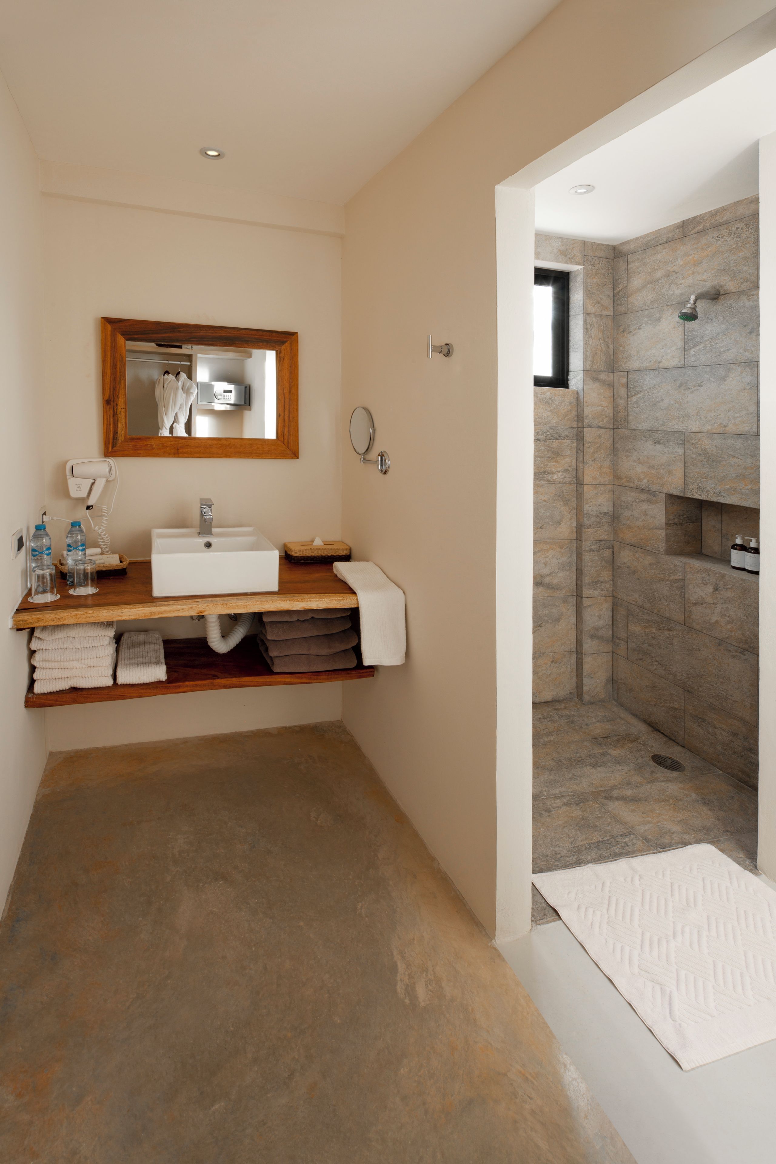 A modern bathroom with a built-in sink, a mirror, a towel rack, and a shower area.
