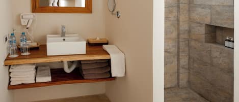 A modern bathroom with a built-in sink, a mirror, a towel rack, and a shower area.