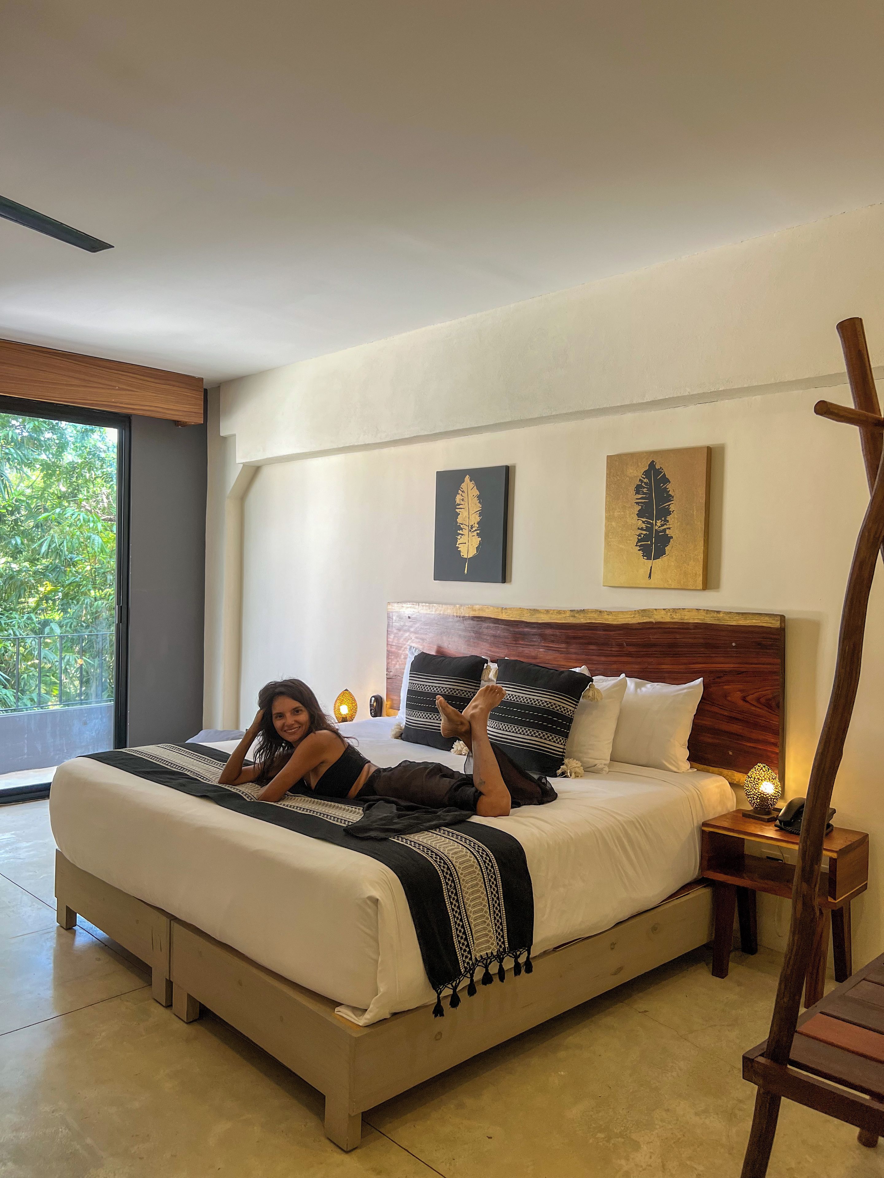 Una camera da letto con un letto, un comodino, una sedia di legno e opere d'arte alle pareti.