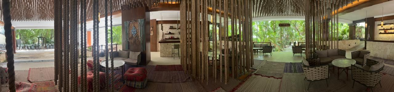 A room with a dining area, a kitchen, and a seating area with a view of the outdoors.
