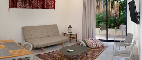 A living room with a sofa, a coffee table, a patterned rug, and a television mounted on the wall.
