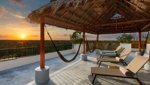 A rooftop terrace with a thatched roof, lounge chairs, and a hammock. - Sunday Hotel Naala Tulum (Tulum)