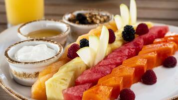Un plato de frutas variadas y un tazón pequeño de yogur.