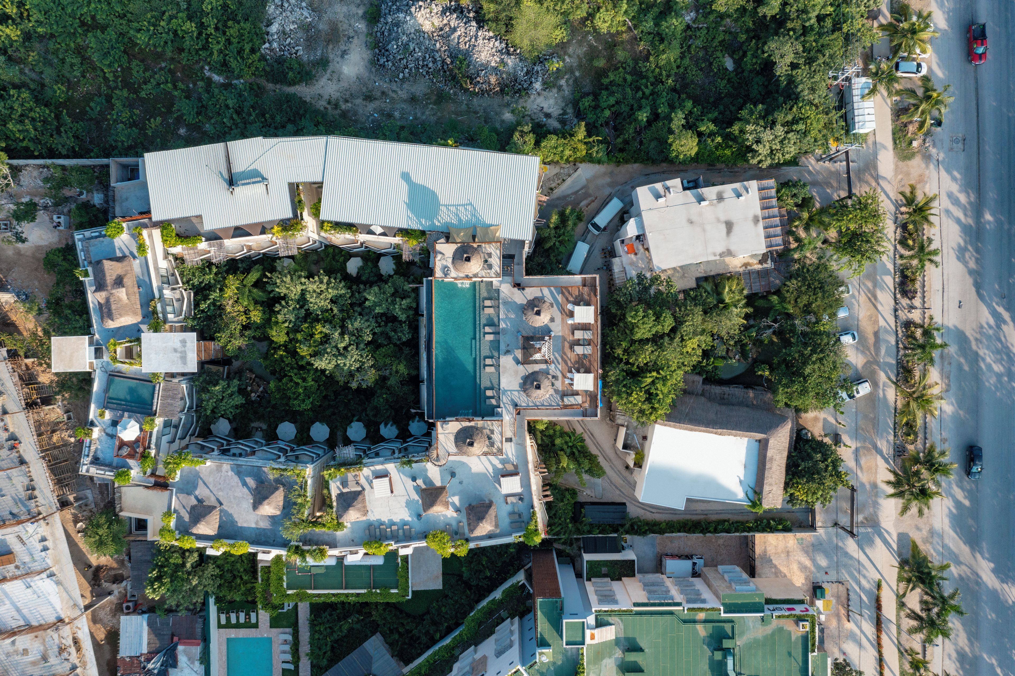 Vista aérea de un resort con varias piscinas, zonas de estar al aire libre y exuberante jardinería.