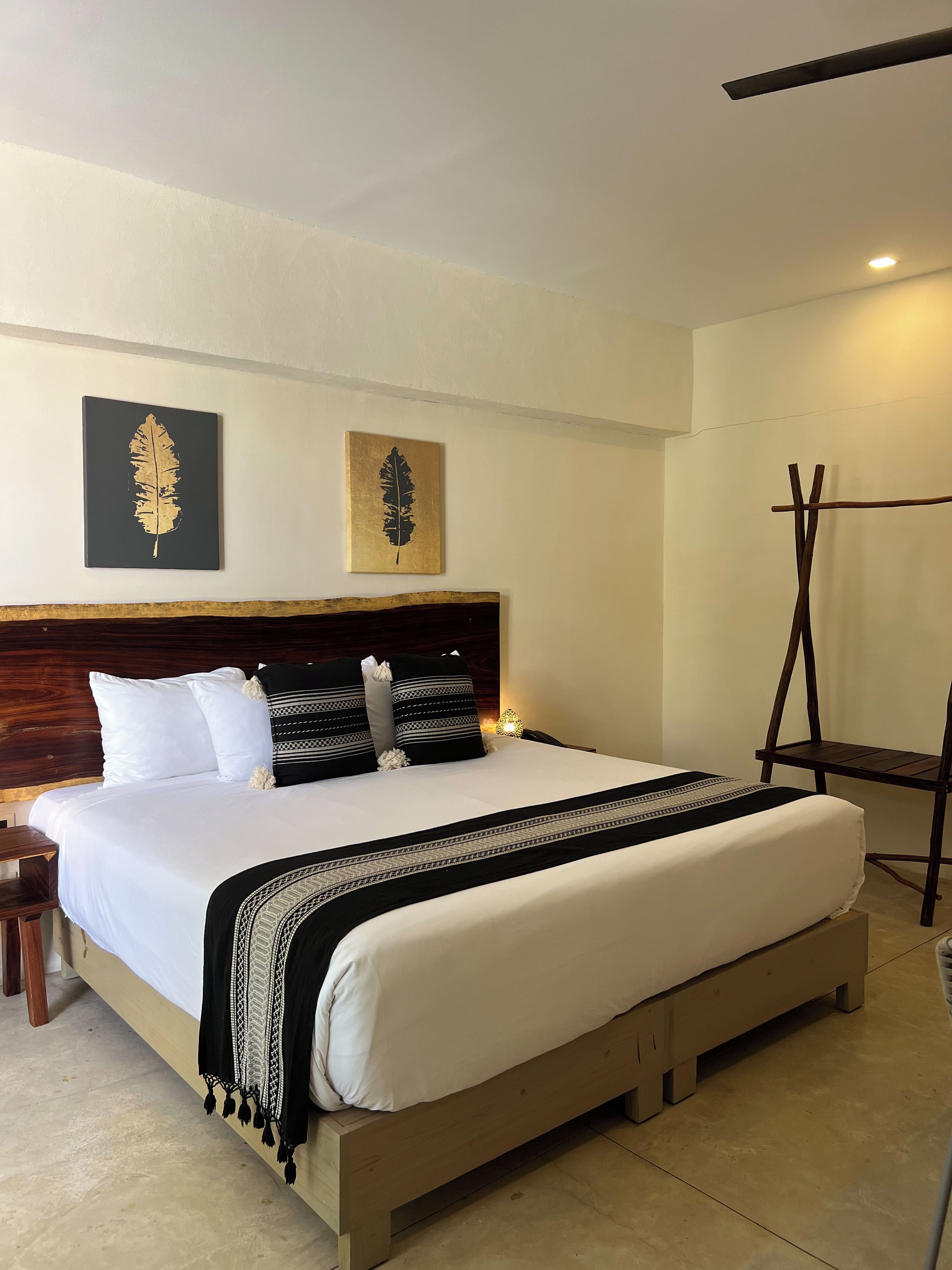 A neatly made bed with a wooden headboard, a bedside table with a lamp, and two wall-mounted artworks.