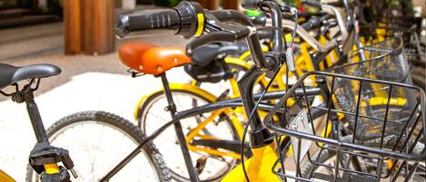 A row of yellow bicycles parked outside a building with a white facade and wooden columns.