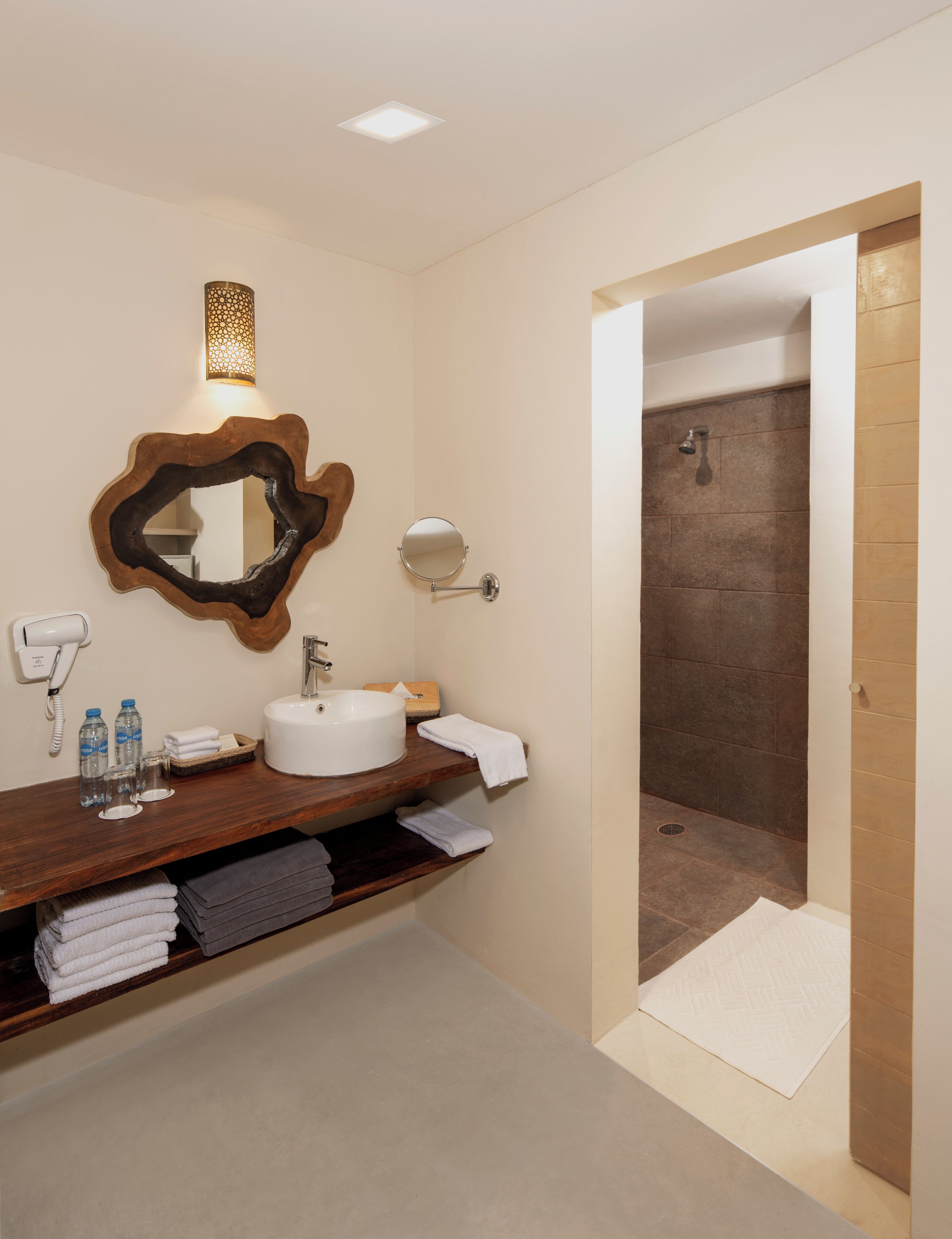 Un bagno moderno con lavabo, specchio, porta asciugamani e zona doccia.
