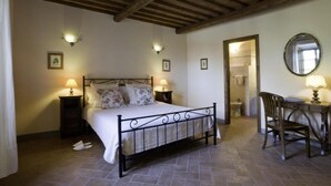 A bedroom with a bed, bedside lamps, a wooden chair, and a desk with a lamp. - Colombaio Apartment (Pietraviva)