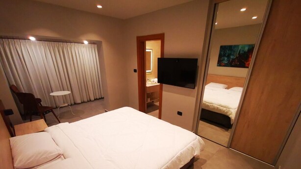 A modern hotel room with a large bed, a desk, a chair, and a television.