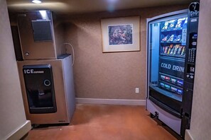 A compact room with a refrigerator, an ice dispenser, and a vending machine.