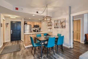 A modern kitchen with wooden cabinets, a central island, and a dining area with blue chairs. - ★★Copper Mountain Center Village Condo that Doesn't Feel Like a Rental!★★ (Frisco)