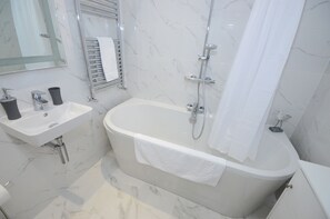 Un baño moderno con lavamanos de mármol, bañera y ducha.