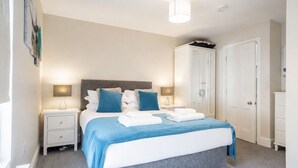 Een slaapkamer met een bed, nachtkastjes, een kledingkast en een plafondlamp.
