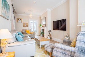 A living room with a sofa, a coffee table, a television, and a fireplace.
