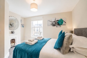Ein Schlafzimmer mit Bett, Kamin, Fenster und Wandbildern.