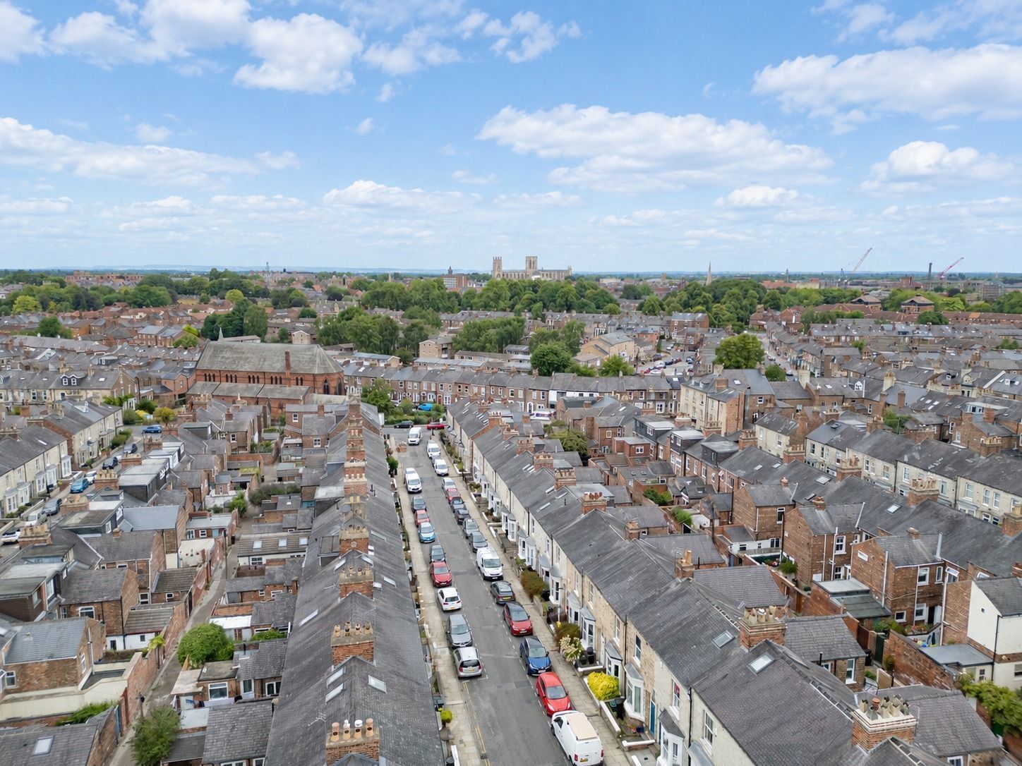 A residential area with terraced houses, a main road, and a distant church tower.