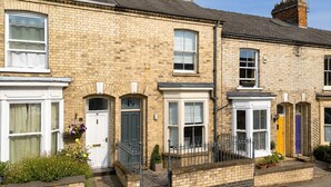 A row of terraced houses with distinct front doors, windows, and a brick facade.