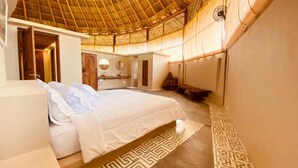 Um quarto espaçoso com uma cama grande, teto de madeira e piso estampado.
