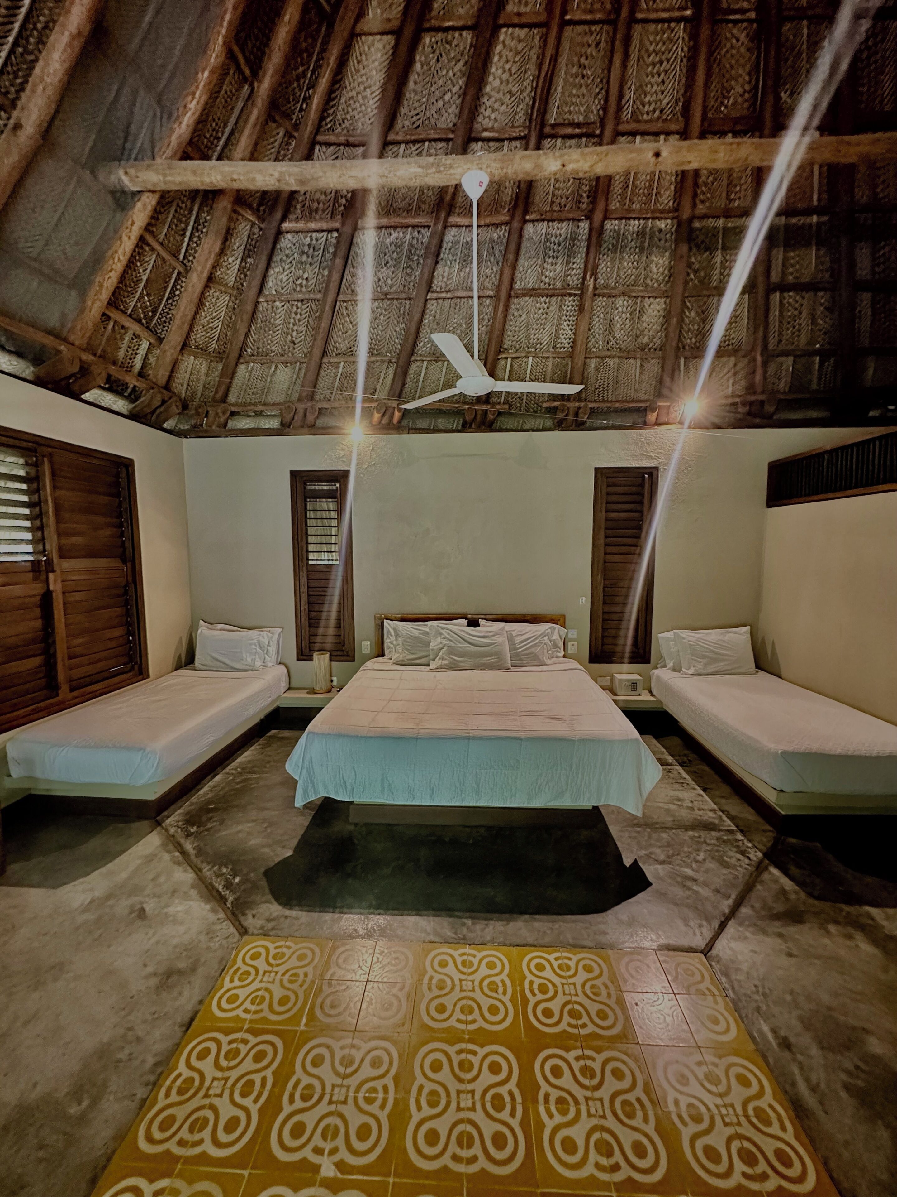A room with a bed, two bedside tables, a ceiling fan, and a patterned floor.
