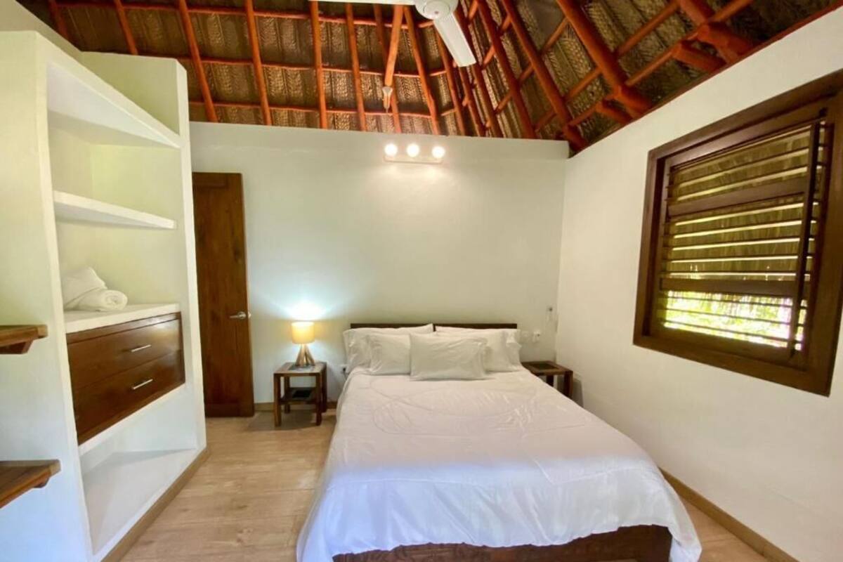 A bedroom with a bed, bedside tables, a nightstand, a lamp, a wardrobe, and a window with blinds.