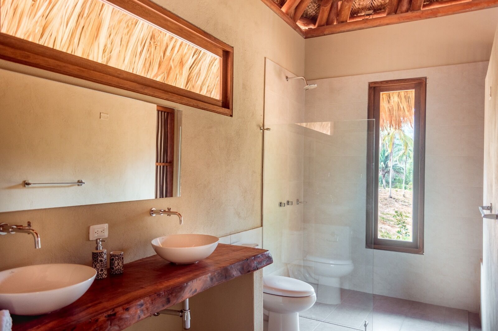 A bathroom with two sinks, a shower, and a large window.