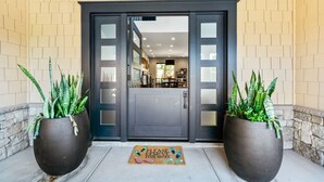 A hotel entrance with a dark door, two large potted plants, and a mat with a shoe removal sign. - 4BR Resort Near Beach/Disney; Pool is +$149 /night (Huntington Beach)