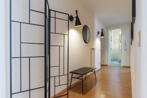 Un couloir doté d’un plancher en bois, d’un banc et de lampes murales noires.