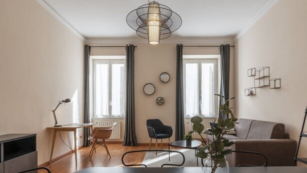 A modern living room with a dining table, two chairs, a sofa, a coffee table, a lamp, and a plant.