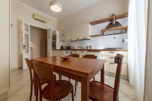 Une cuisine moderne avec des meubles blancs, une table à manger en bois et un four encastré.