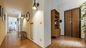 A hallway with wooden flooring, a radiator, a wooden cabinet, a wardrobe, and a plant.