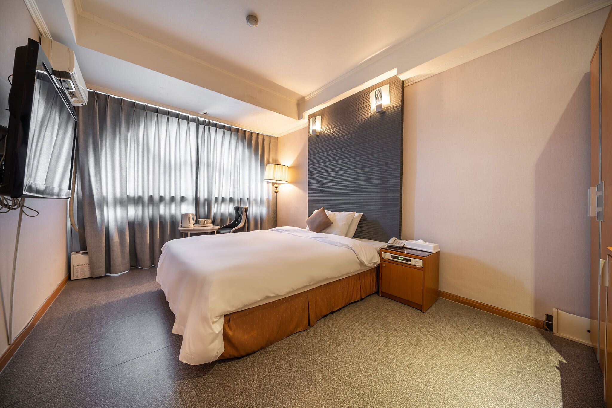 Habitación de hotel con una cama grande, un escritorio, una silla, una lámpara y un televisor de pantalla plana.