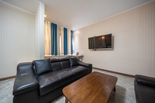 Una sala de estar moderna con un sofá de cuero, una mesa de centro de madera y un televisor de pantalla plana montado en la pared.
