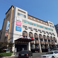 Un hotel de varios pisos con fachada moderna, múltiples balcones y varios rótulos comerciales en la planta baja.