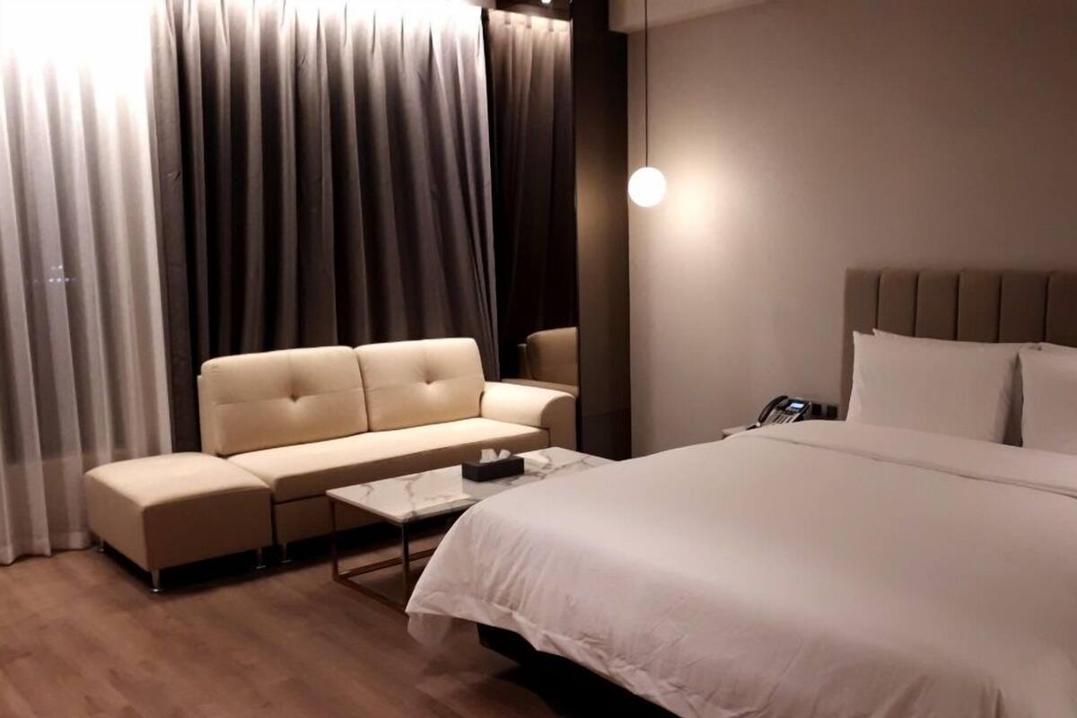 A hotel room with a bed, a sofa, a coffee table, and a telephone.