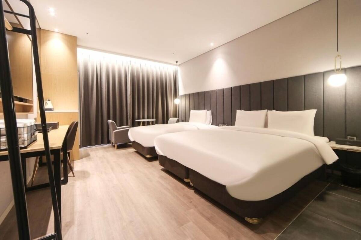 A modern hotel room with a large bed, a desk, and a chair.
