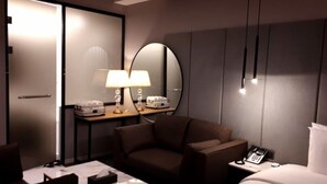 A hotel room with a bed, a desk, a chair, a bedside table with a lamp, a mirror, and a telephone. - Busan Myeongji Ciel Ocean Hotel (Busan)