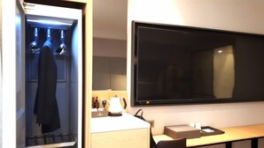 A hotel room with a wardrobe, a desk with a flat-screen TV, and a small table with a lamp. - Busan Myeongji Ciel Ocean Hotel (Busan)
