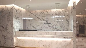A hotel reception desk with marble walls and a modern design. - Busan Myeongji Ciel Ocean Hotel (Busan)