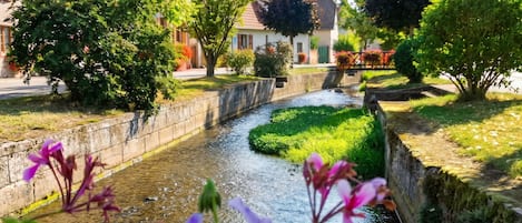 Ein schmaler Wasserlauf, an einer Seite eine Steinmauer und am anderen ein grünes Ufer mit Bäumen.