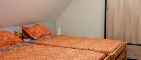 A bedroom with a sloped ceiling, a wooden bed frame, and a wooden wardrobe.