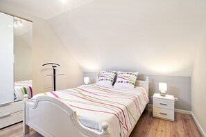 Ein Schlafzimmer mit einem Bett, Nachttischen, einem Spiegel und einer Lampe.