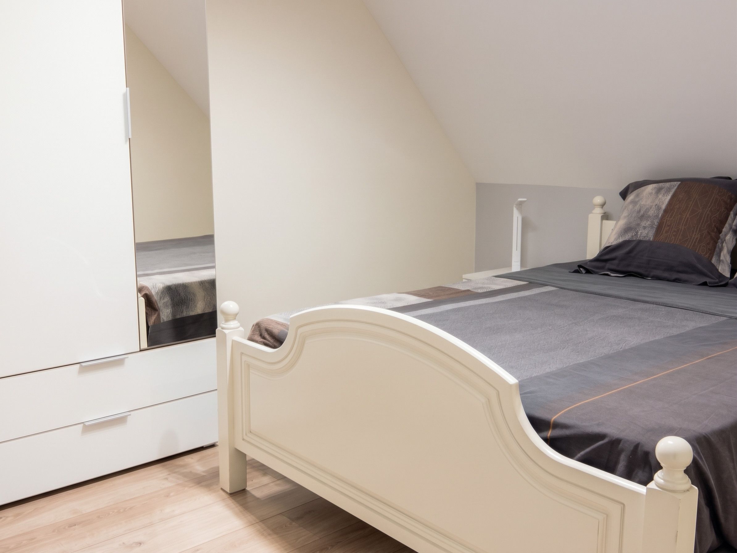 Ein Schlafzimmer mit einem Bett, einem Kleiderschrank und einem Spiegel.