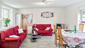 Una sala de estar moderna con un sofá rojo, una mesa de comedor con mantel estampado y una lámpara en el techo.