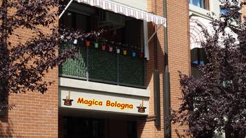 Un bâtiment sur lequel on peut lire l’inscription « Magica Bologna », et qui possède un balcon décoré de motifs colorés.