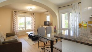 A modern living room with a glass dining table, a sofa, and a TV in the background. - Vacation home Alexia by Interhome (Benissa)